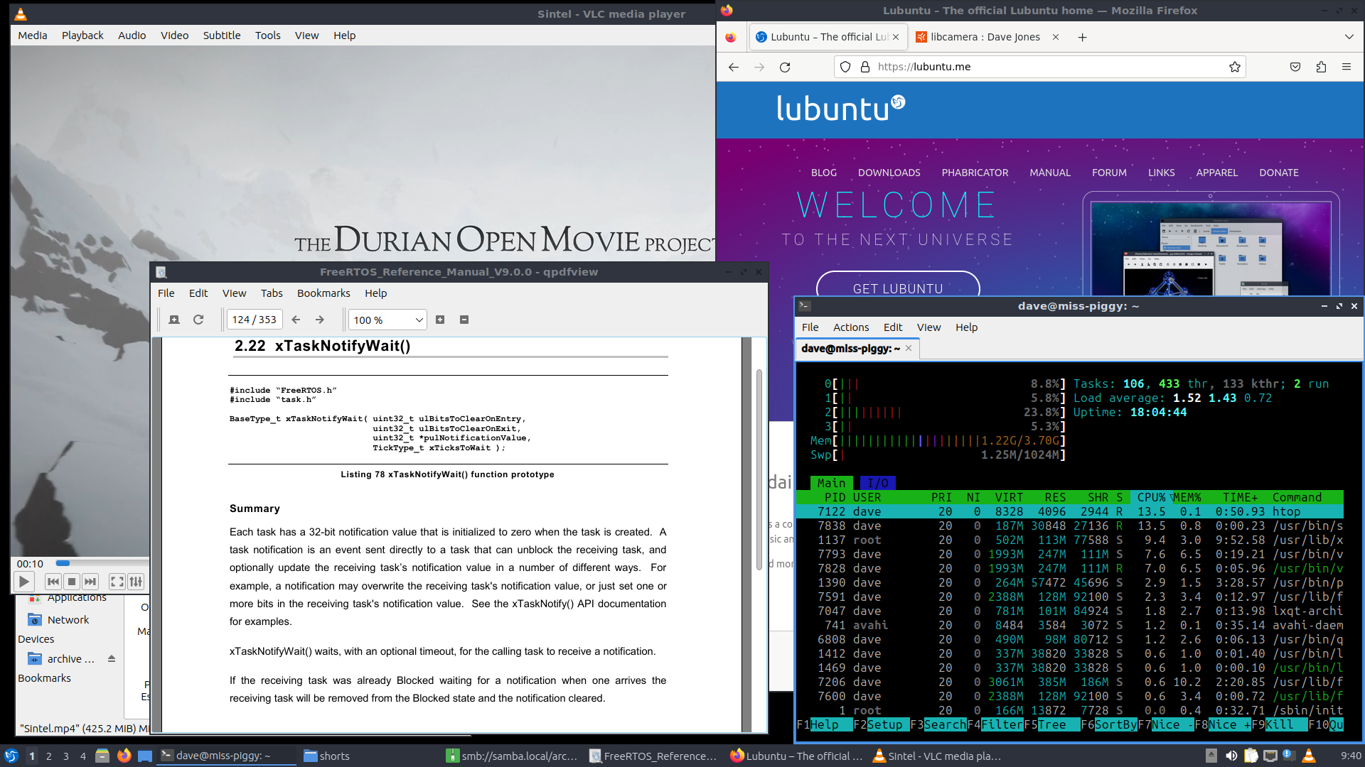 A screenshot of the Lubuntu desktop. A small panel sits at the bottom of the screen showing (from left to right) the small applications menu button (adorned with a bird), the numbers 1 through 4 for the desktop switcher, some quick-launch icons for the file-manager and firefox, the window switcher, and the small icons in the system tray, followed by the clock. Above are numerous overlapping windows including a PDF showing a section of the FreeRTOS manual datasheet, "htop" running in a terminal, "Sintel" playing in VLC, a file browser, and Firefox showing the Lubuntu homepage.